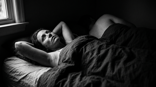 Femme éveillée dans le noir à côté de son conjoint endormi, photographie en noir et blanc