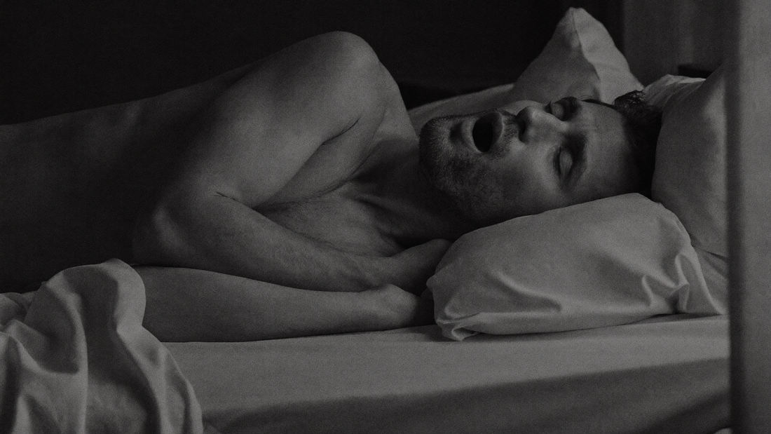 Homme allongé sur le dos dans son lit la nuit, éveillé, la bouche entrouverte parce que son nez est bouché