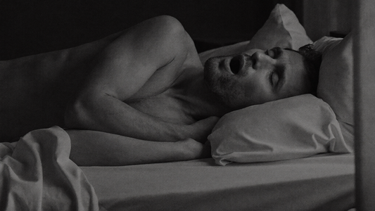 Homme allongé sur le dos dans son lit la nuit, éveillé, la bouche entrouverte parce que son nez est bouché